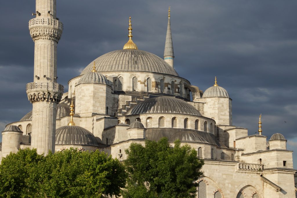 Sultan Ahmet Camii ( Blue Mosque ) glows in early evening light against dark clouds in the background in Istanbul, Turkey